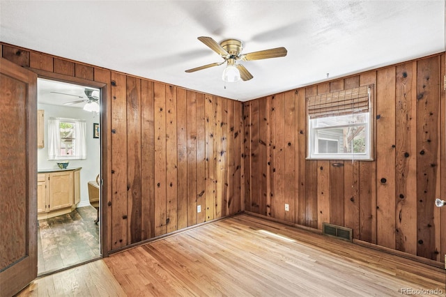 4285 Newland St, Wheat Ridge, CO 80033 - empty room with light wood-style flooring, a ceiling fan, wood walls, and baseboards