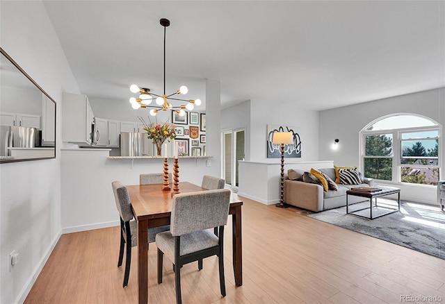 dining area featuring an inviting chandelier, light wood-style flooring, and baseboards