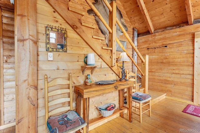 stairs with beamed ceiling, hardwood / wood-style floors, wooden ceiling, and wood walls