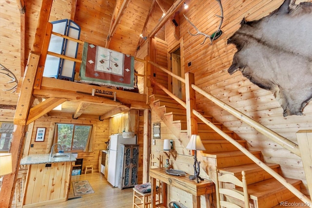 stairway featuring beam ceiling, sink, wooden walls, wood ceiling, and hardwood / wood-style flooring