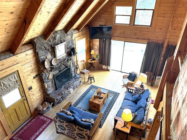 living room featuring wood ceiling, a fireplace, vaulted ceiling with beams, light hardwood / wood-style floors, and wood walls