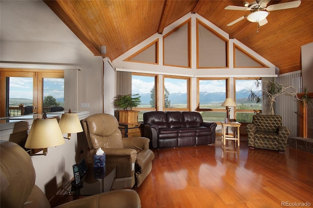 living room with wood-type flooring, a mountain view, beam ceiling, and ceiling fan