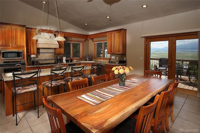 tiled dining space featuring vaulted ceiling, a textured ceiling, and french doors