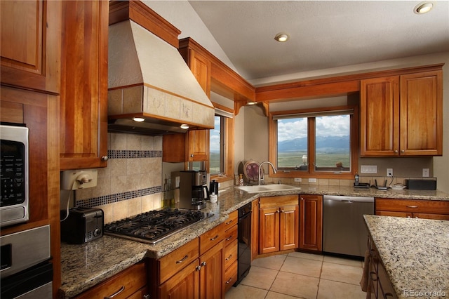 kitchen with appliances with stainless steel finishes, sink, custom exhaust hood, and light stone counters