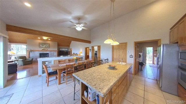 kitchen with a center island, a tile fireplace, hanging light fixtures, light stone countertops, and ceiling fan