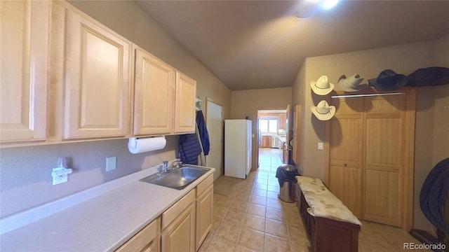 kitchen featuring light brown cabinets, white refrigerator, sink, and light tile patterned flooring