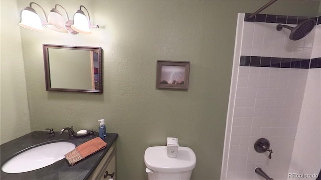 bathroom with a tile shower, vanity, and toilet