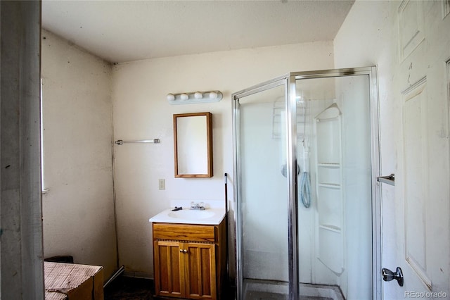 bathroom featuring a shower with door and vanity