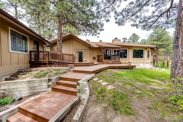 8788 E Tanglewood Rd, Franktown, CO 80116 - back of property with board and batten siding, a chimney, a deck, and a yard