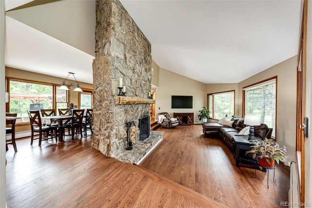 8788 E Tanglewood Rd, Franktown, CO 80116 - living room featuring a stone fireplace, wood finished floors, baseboard heating, and high vaulted ceiling