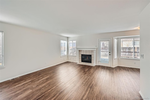 unfurnished living room with dark hardwood / wood-style floors, a tile fireplace, and plenty of natural light