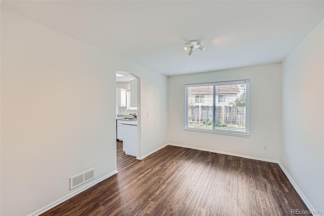 spare room featuring sink and dark wood-type flooring