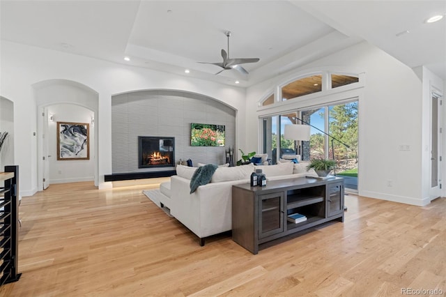 living room with ceiling fan, a tile fireplace, and light hardwood / wood-style flooring