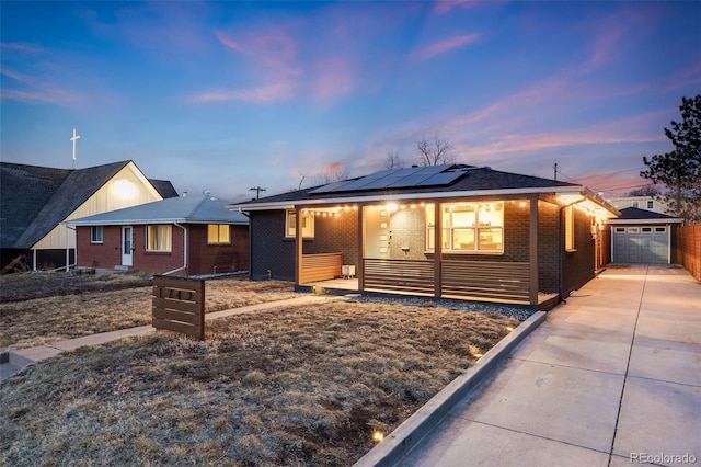 single story home featuring a garage, concrete driveway, an outbuilding, roof mounted solar panels, and brick siding