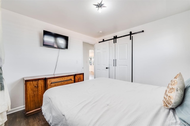 bedroom featuring dark wood-style floors, a barn door, and baseboards