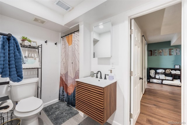 bathroom featuring visible vents, toilet, wood finished floors, and vanity