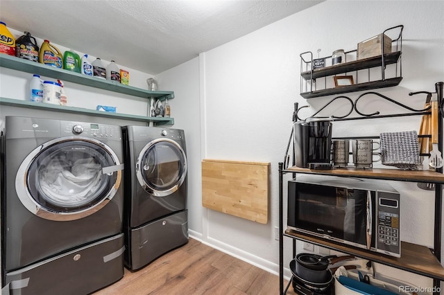 laundry room featuring a textured ceiling, laundry area, wood finished floors, baseboards, and washer and clothes dryer