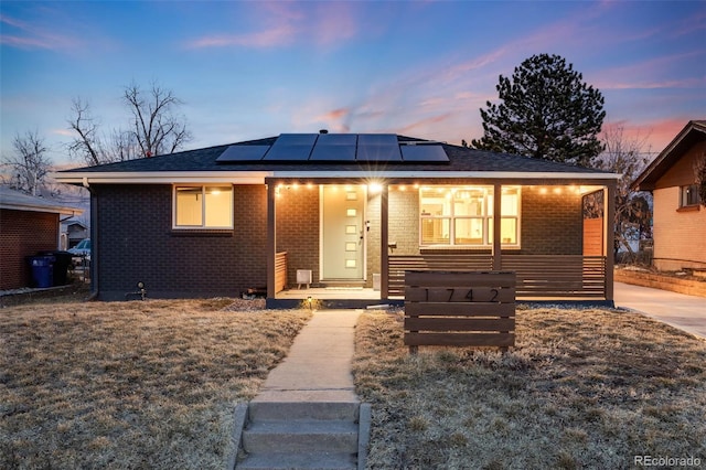 1742 S Alcott St, Denver, CO 80219 - view of front of house with brick siding, roof mounted solar panels, and a porch