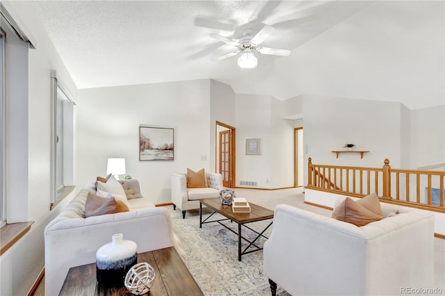 living room featuring a textured ceiling, ceiling fan, light hardwood / wood-style flooring, and vaulted ceiling