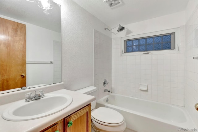 bathroom featuring visible vents, toilet, shower / bathtub combination, a textured wall, and vanity