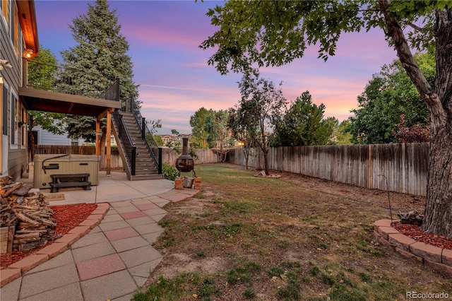 yard at dusk featuring a patio area and a hot tub