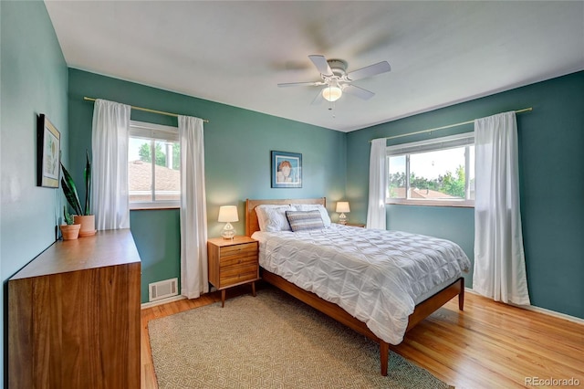 bedroom with ceiling fan, light wood-type flooring, and multiple windows