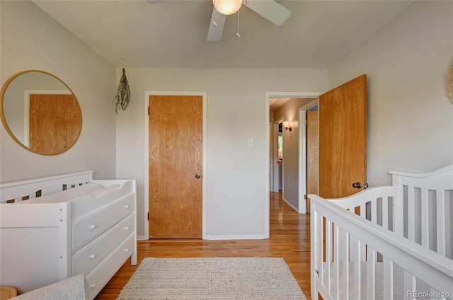 bedroom with ceiling fan, hardwood / wood-style floors, and a crib