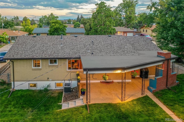 back house at dusk featuring a yard and a patio