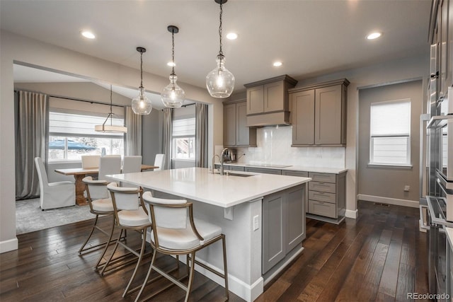 kitchen with black electric stovetop, a sink, backsplash, and gray cabinetry