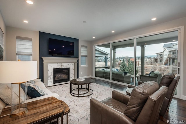 living area featuring a high end fireplace, baseboards, recessed lighting, and wood finished floors