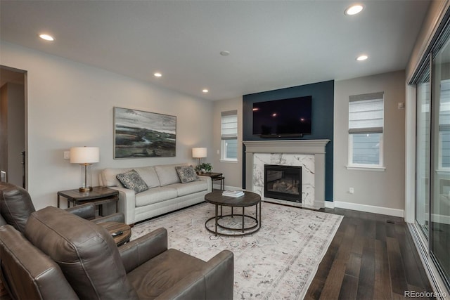 living area featuring recessed lighting, baseboards, dark wood-type flooring, and a high end fireplace