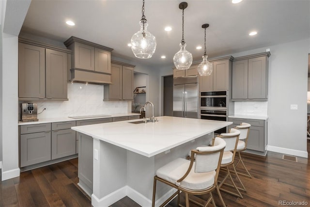 kitchen featuring built in refrigerator, a sink, and gray cabinetry