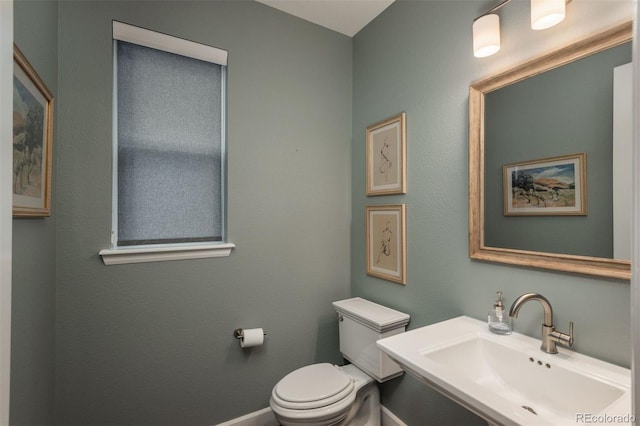 bathroom with toilet, baseboards, and a sink