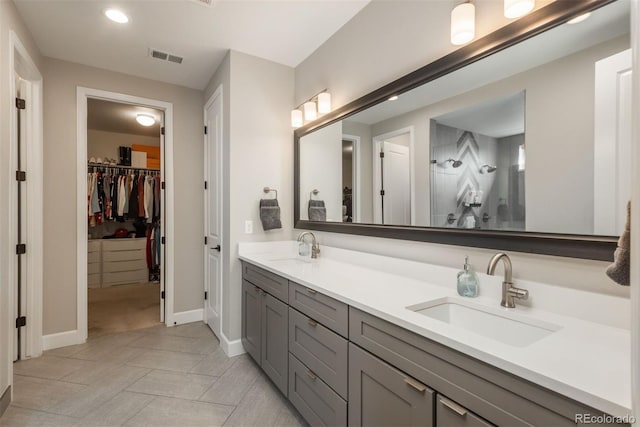 bathroom featuring double vanity, a spacious closet, baseboards, and a sink