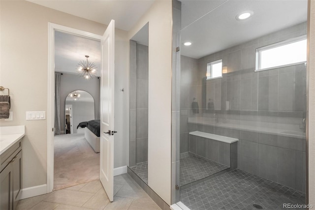 ensuite bathroom featuring ensuite bathroom, vanity, baseboards, tile patterned floors, and walk in shower