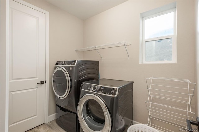 clothes washing area with washing machine and dryer, laundry area, and baseboards