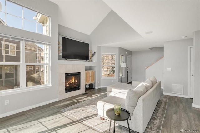 living room with a tile fireplace, wood finished floors, visible vents, and a healthy amount of sunlight