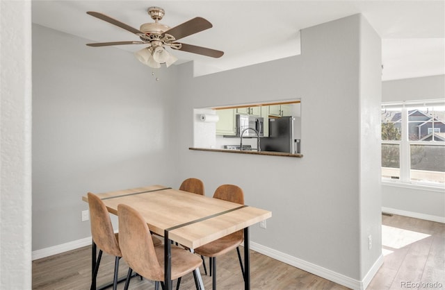 dining room featuring wood finished floors, a ceiling fan, and baseboards