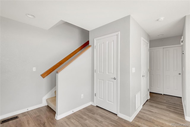 corridor featuring wood finished floors, visible vents, baseboards, and stairs