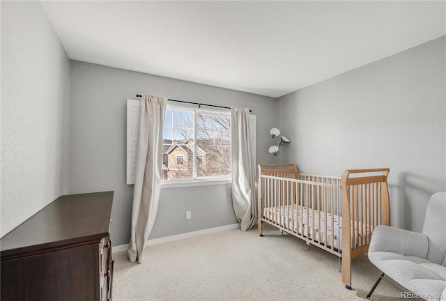 bedroom with a crib, carpet, and baseboards