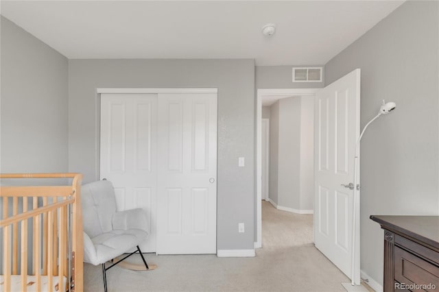 bedroom with baseboards, visible vents, a closet, and light colored carpet