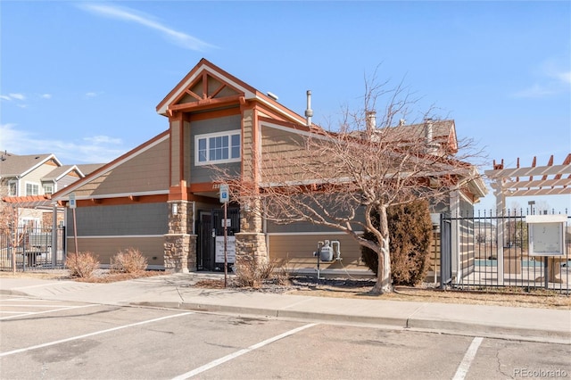 view of front of house featuring uncovered parking, fence, and a gate