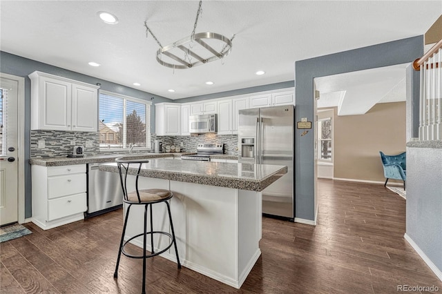 kitchen featuring a center island, white cabinetry, dark wood-type flooring, and appliances with stainless steel finishes