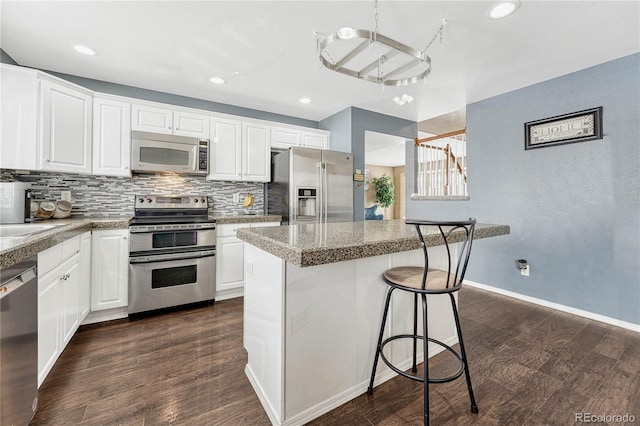 kitchen with a kitchen island, white cabinetry, stainless steel appliances, and dark wood-type flooring