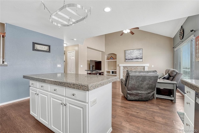 kitchen with a center island, white cabinets, ceiling fan, built in features, and a fireplace