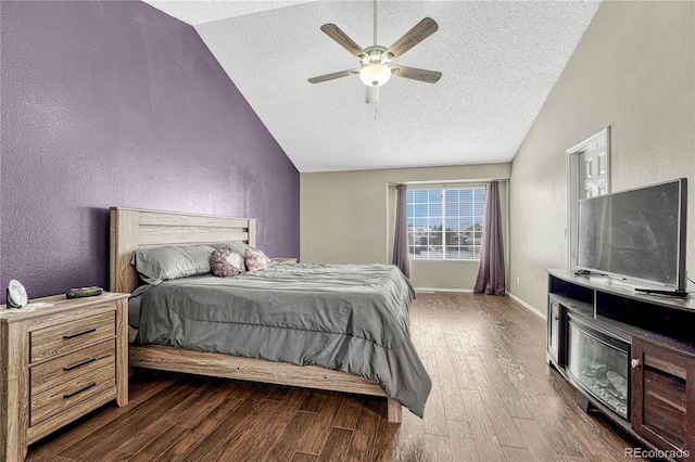 bedroom featuring a textured ceiling, ceiling fan, dark wood-type flooring, and vaulted ceiling