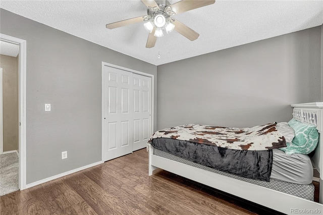 bedroom with ceiling fan, a closet, dark wood-type flooring, and a textured ceiling