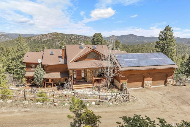 rustic home with roof mounted solar panels, covered porch, a mountain view, and stone siding