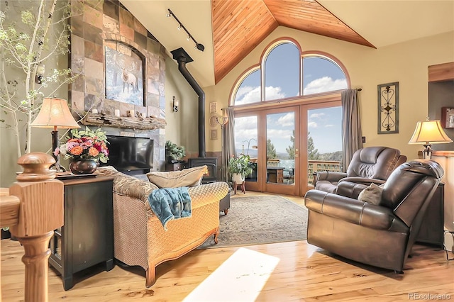 living room with hardwood / wood-style flooring, wood ceiling, a wood stove, and high vaulted ceiling