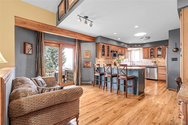 kitchen featuring a peninsula, appliances with stainless steel finishes, a breakfast bar area, and glass insert cabinets